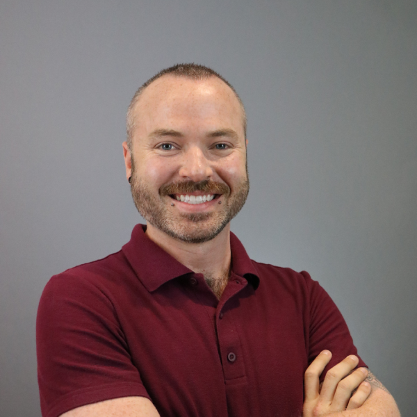 Justin Snow, Career Development & Alumni Relations Counselor for the MIT Supply Chain Management Master’s Program, standing smiling with arms folded