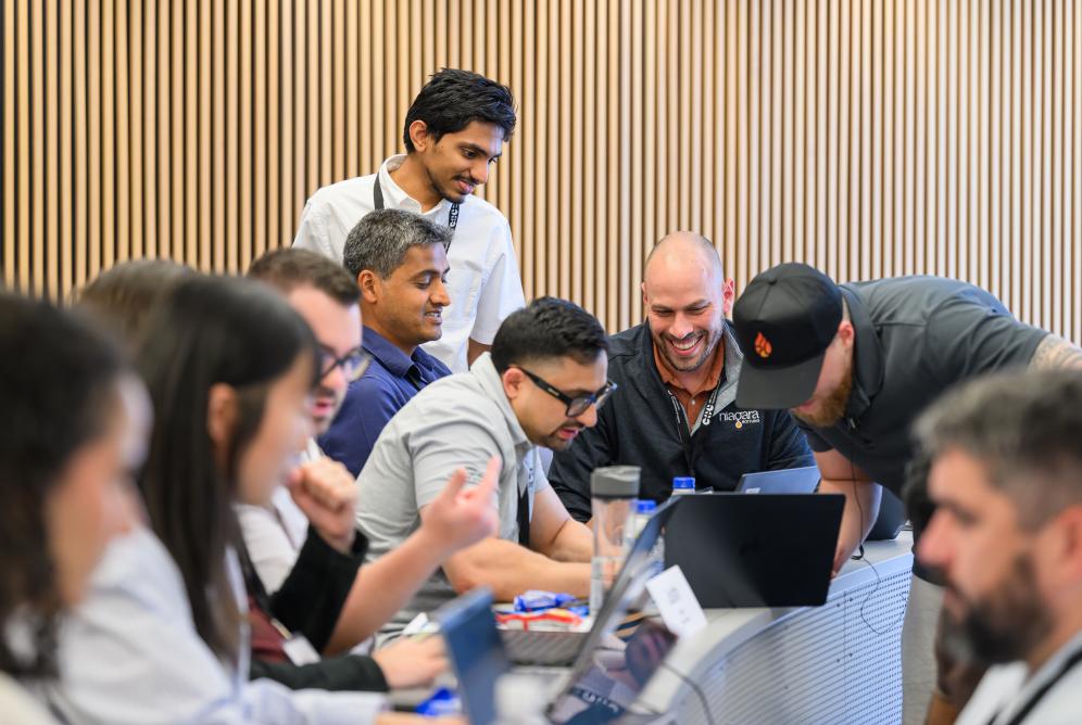 people in a group looking at a shared laptop. 