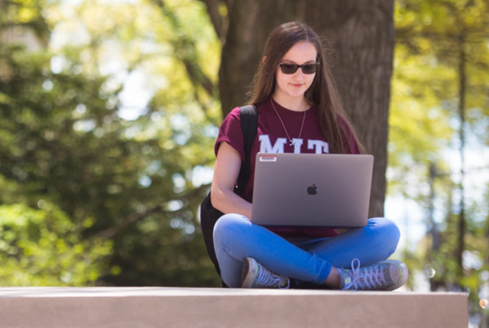 MIT student studying outdoors on a laptop