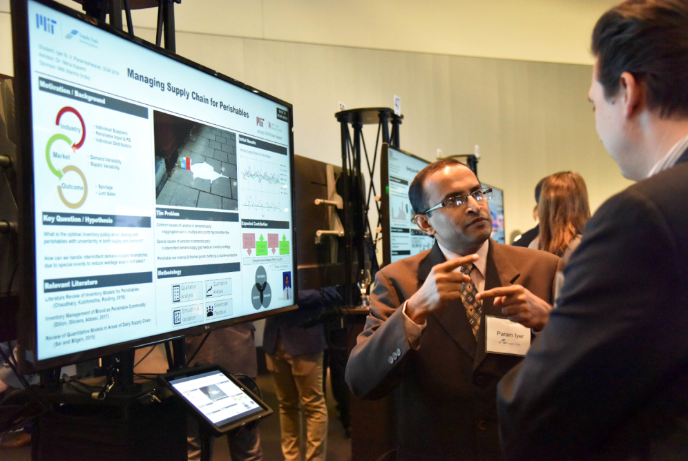 Man explaining electronic research poster screen to another man