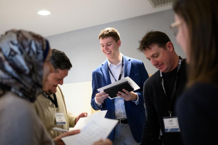 Man standing among peers - looking at papers