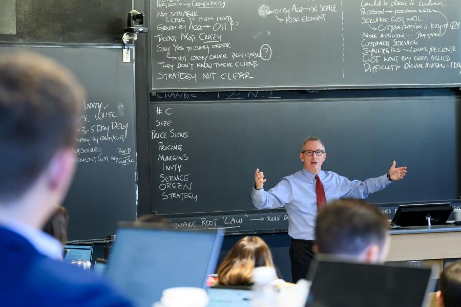 Instructor in classroom in front of chalkboard